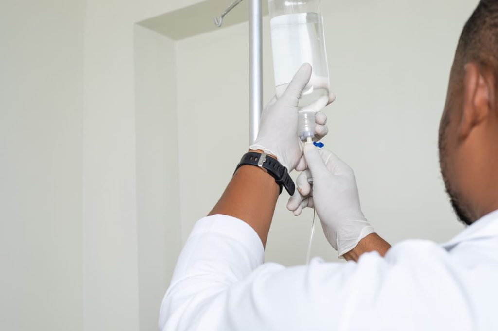 Ozone Therapy A medical professional in a white coat and gloves preparing an IV drip for Ozone therapy at German Ozone Medical Centre, ensuring proper setup and sterilisation.