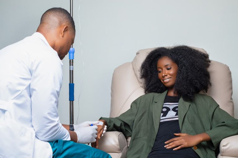 A woman receiving IV therapy from a healthcare professional at German Ozone Medical Centre, looking relaxed and comfortable.