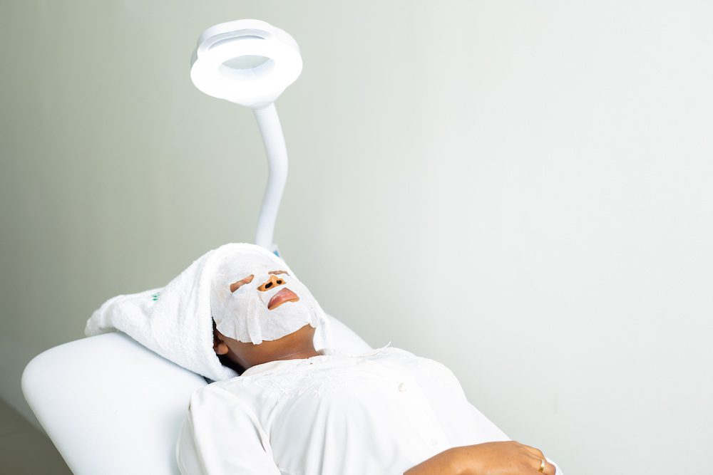 Ozone Skincare Therapy A woman relaxing on a treatment bed with a white facial mask and a towel wrapped around her head in German Ozone Medical Centre.