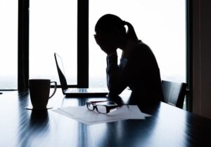 Stressed woman at work with head in hands, showing fatigue — ozone therapy can help reduce stress and improve well-being.